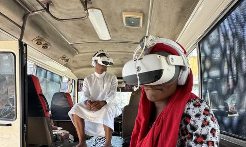 2 visitors sit with VR glasses in the Daladala (bus).