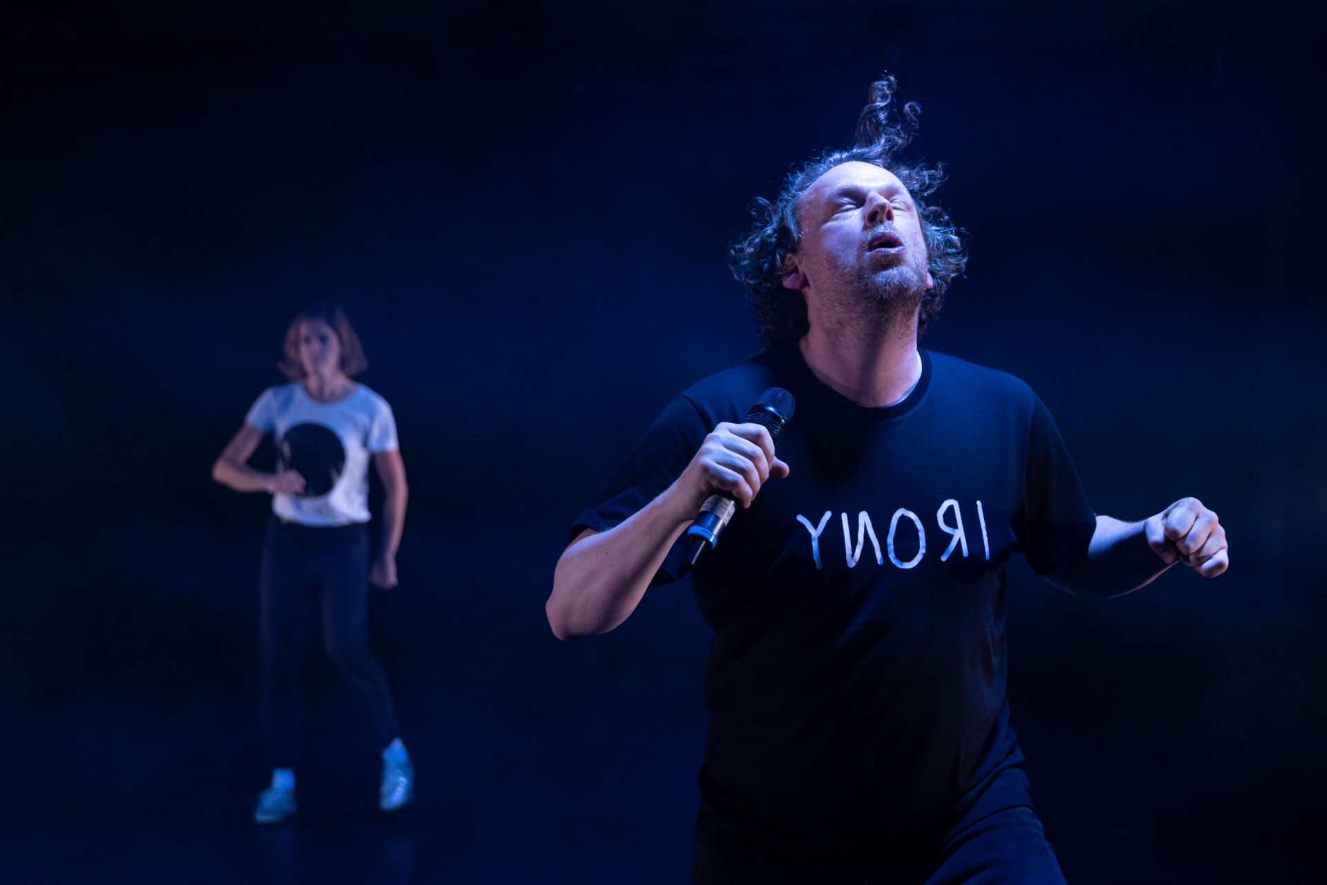 Bühnenszene von Oh Man! … 2 Schauspieler*innen in Bewegung auf dunkler Bühne